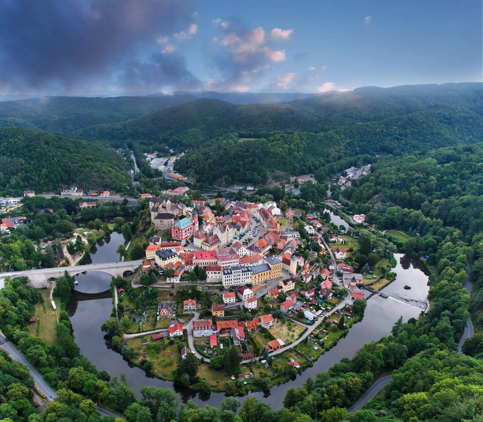 Historické město Loket v ohybu řeky, kolem zalesněné kopce
