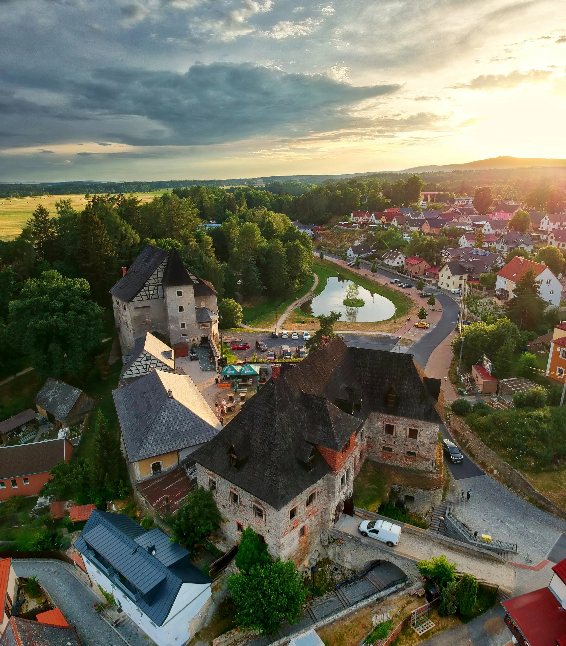 Hrad Vildštejn s vysokými střechami nad Skalnou při západu slunce