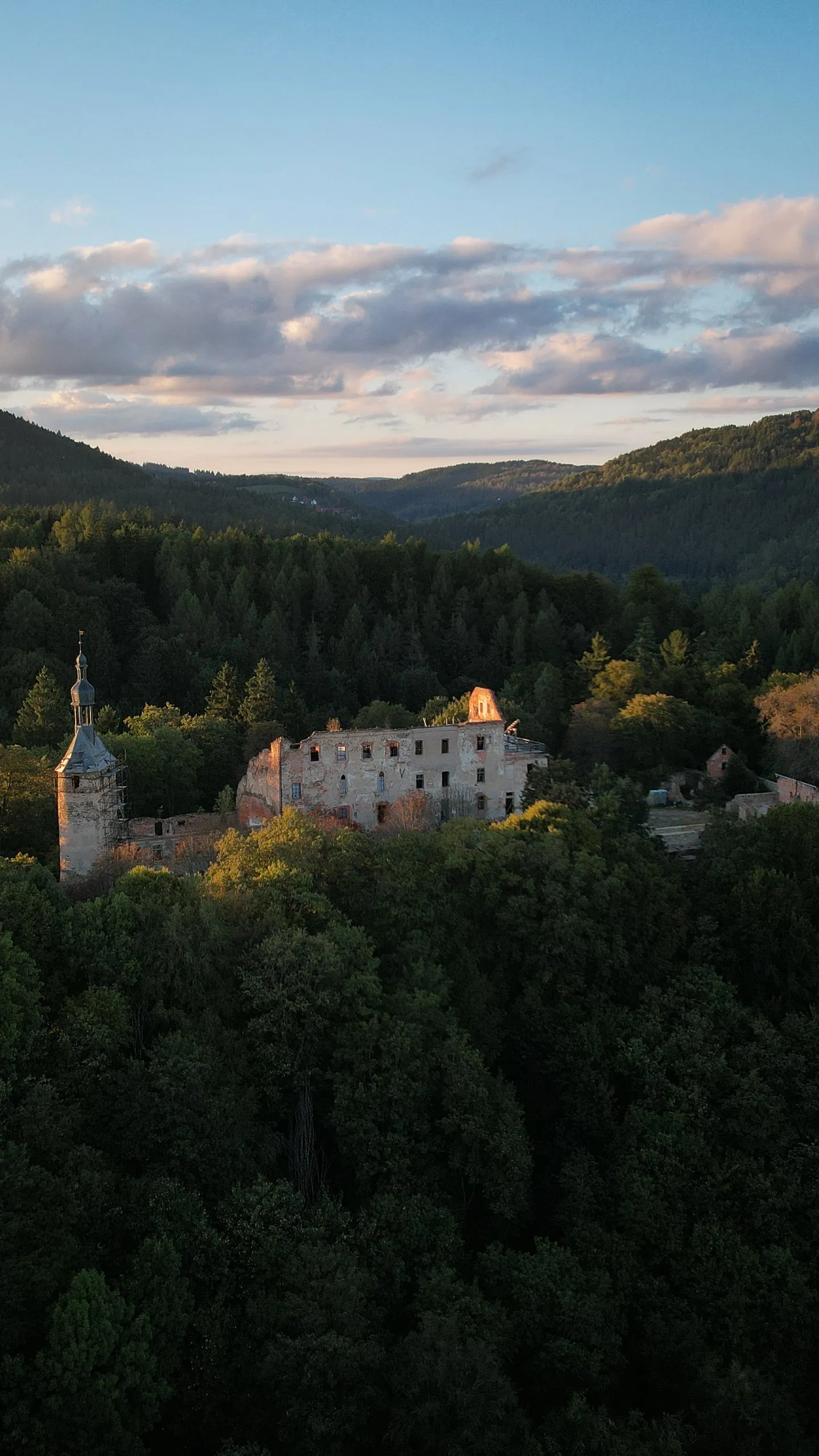Zřícenina hradu Hartenberg nad tmavým lesem, v pozadí zalesněné kopce