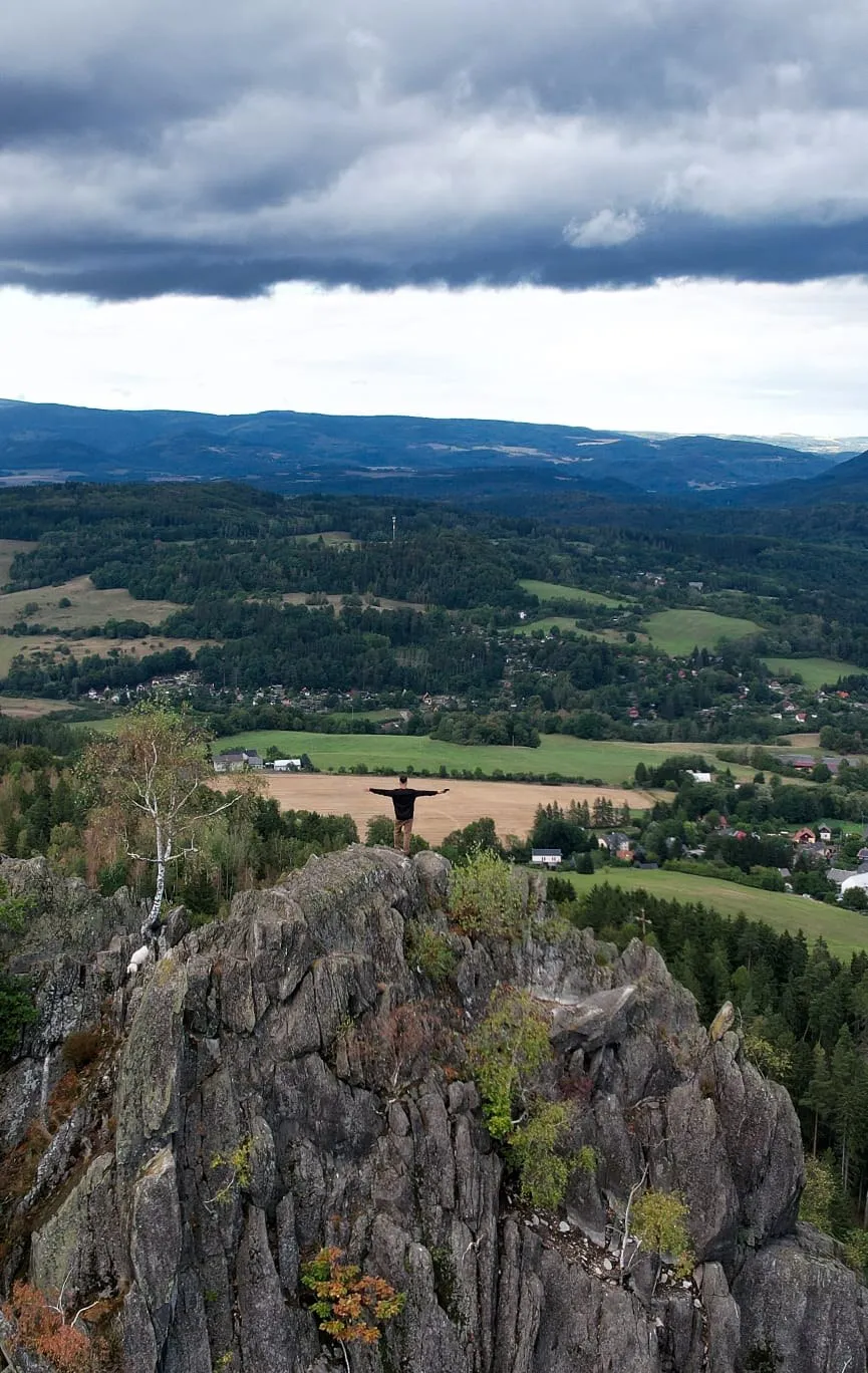 Postava na skalním výchozu nad krajinou, snímek z dronu